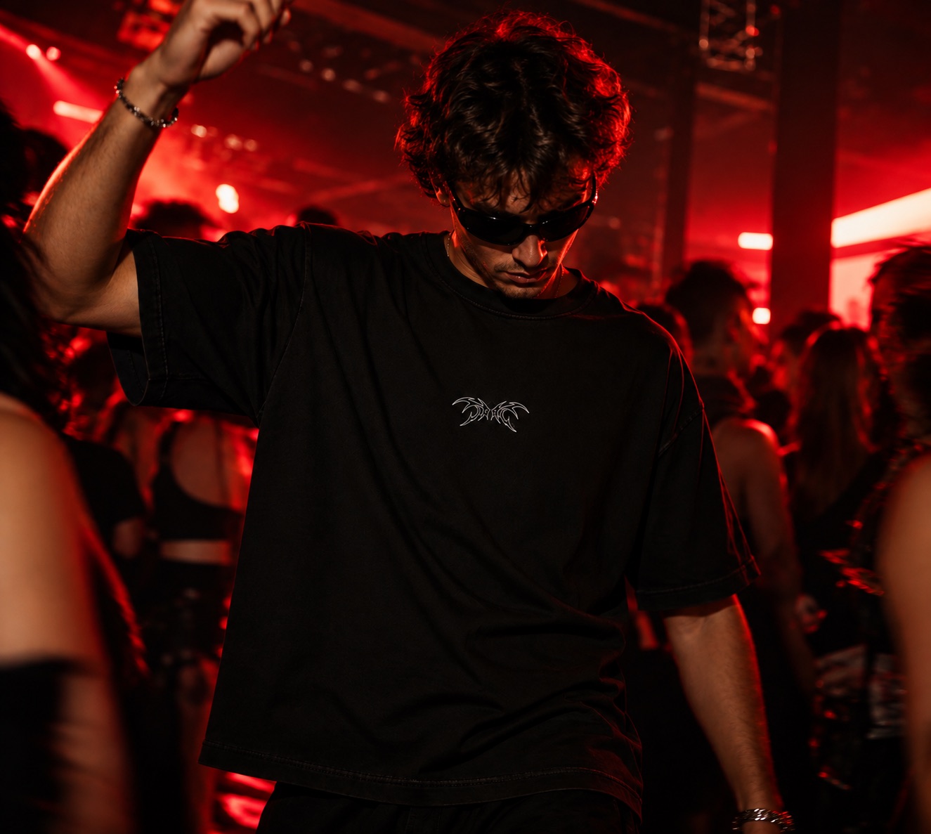 Un garçon danse en rave sous les lumières rouges, t-shirt noir French is Techno avec le petit logo ailes